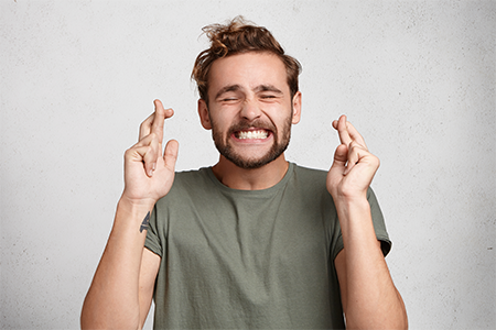 Man crossing his fingers hoping for good luck.