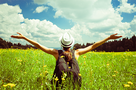 Woman with wide open arms in field on summer solstice.