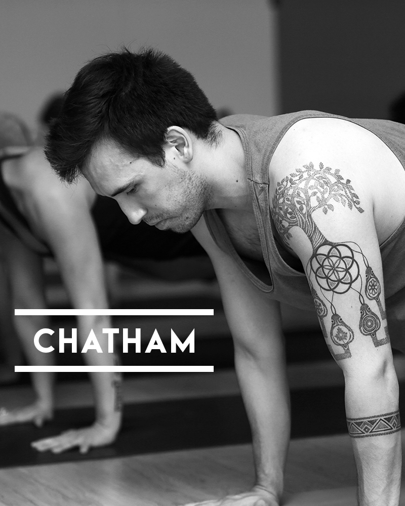 Students holding plank pose in a hot power yoga class in Chatham, New Jersey.