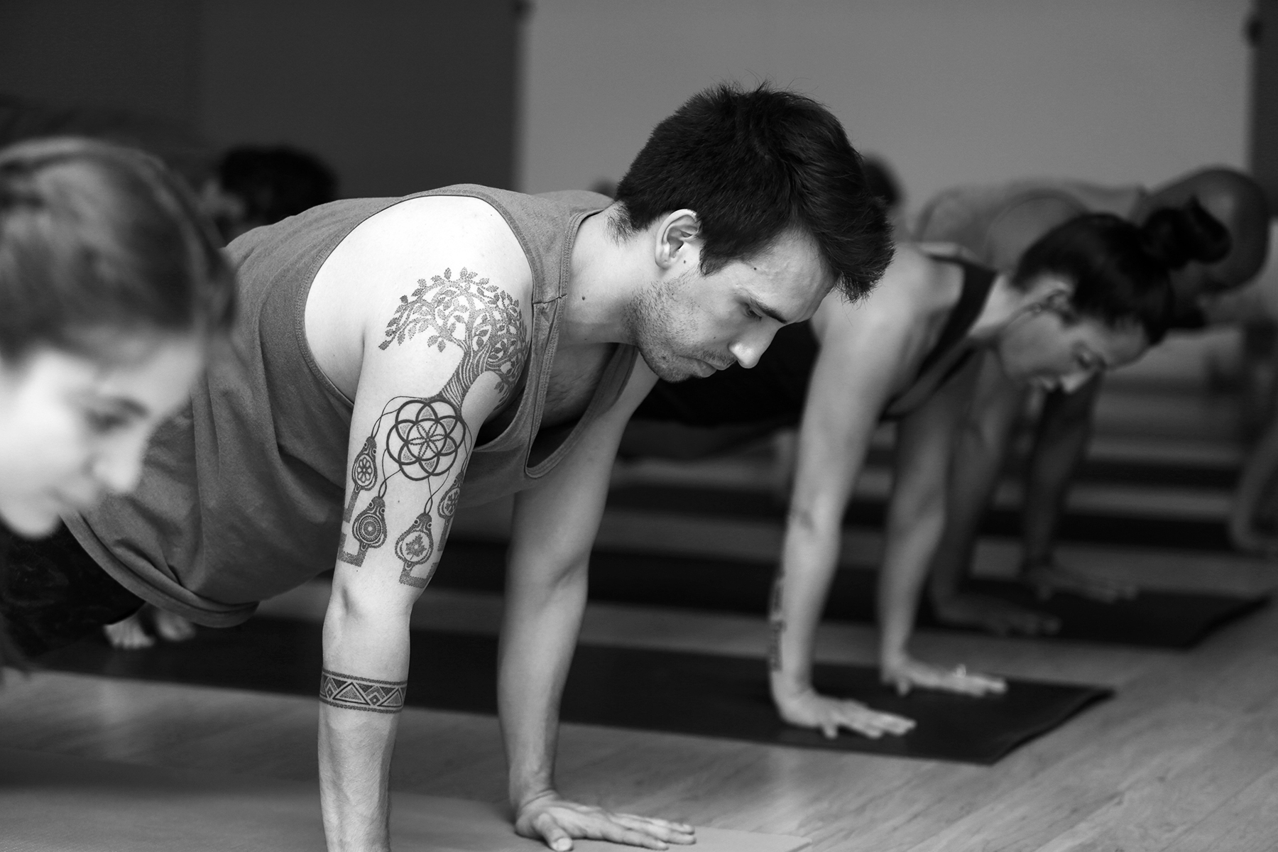 Man with tattoos in plank pose at Powerflow Yoga.