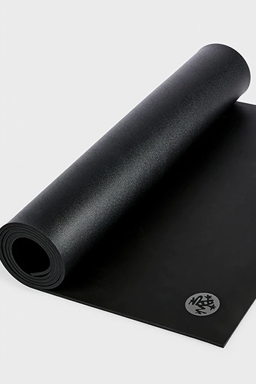 Image shows a black Manduka yoga mat almost completely rolled up.